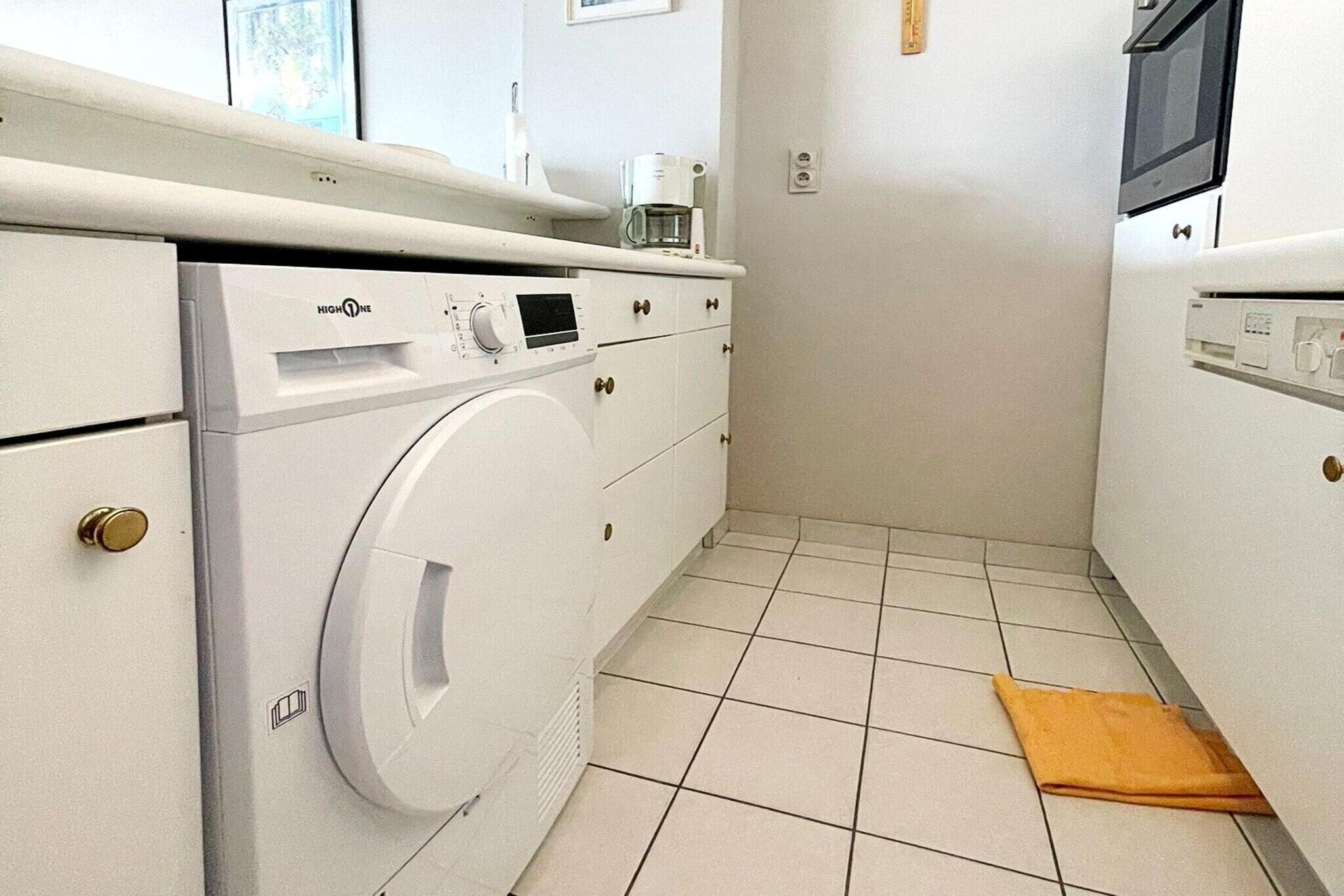 A compact kitchen with a washing machine, a microwave, and a coffee maker on the counter.