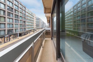 En hög byggnad med flera våningar, stora fönster och en gångväg för fotgängare på markplan.
