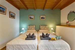Un lit double avec des serviettes, deux tables de chevet avec des lampes, des tableaux encadrés au mur et un miroir.