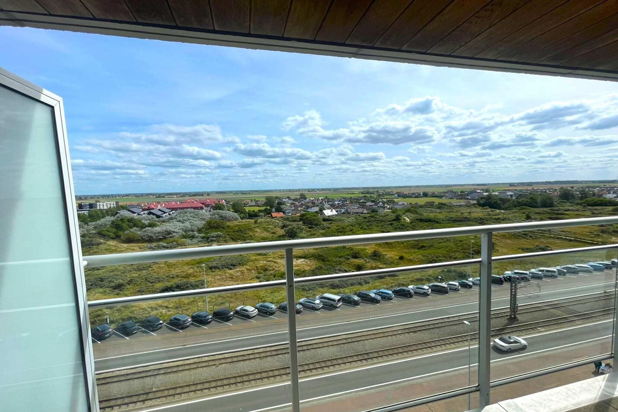 Udsigt fra en balkon over en motorvej med biler og jernbane.