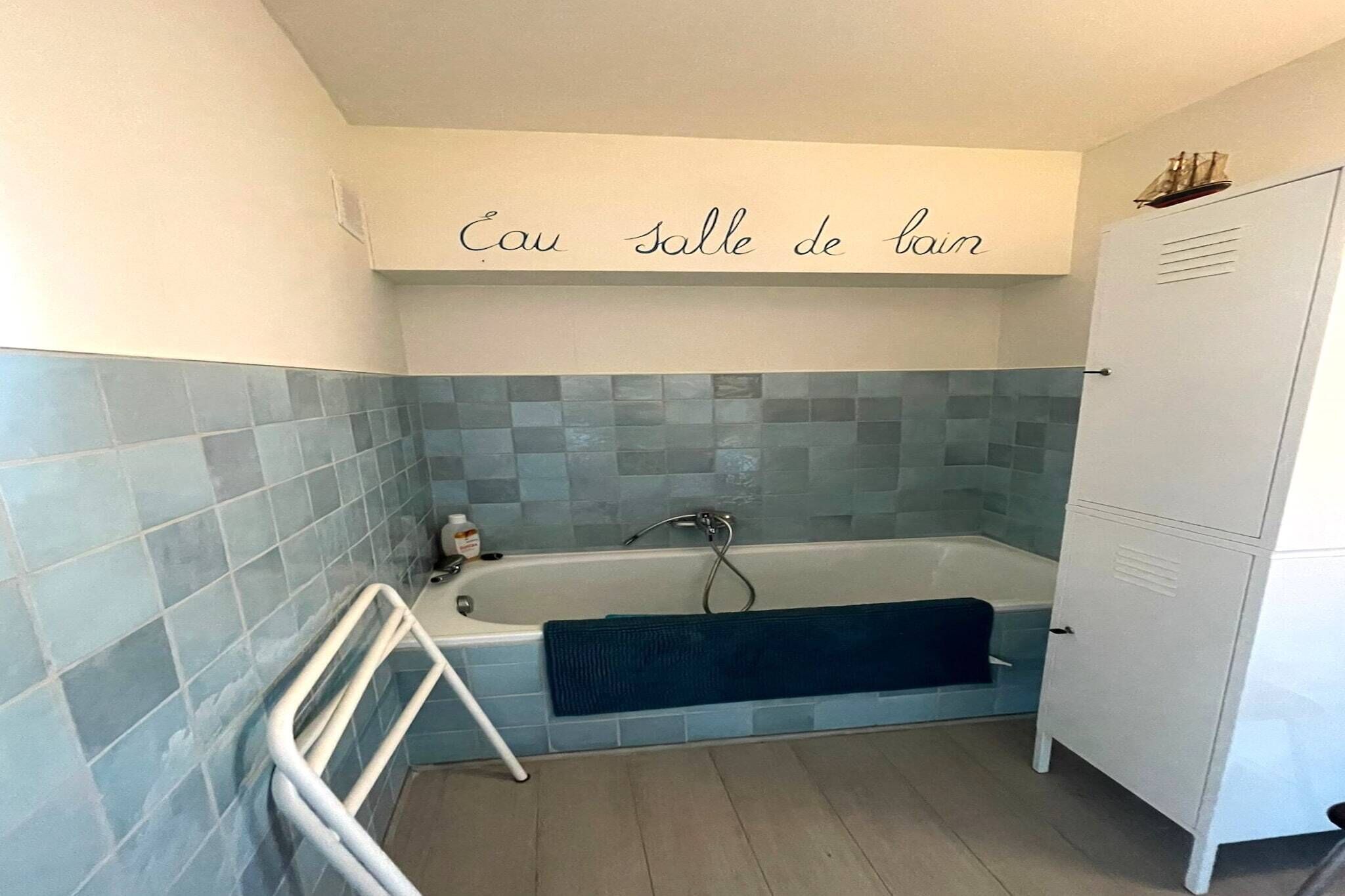 A bathroom with a bathtub, a towel rack, and a cabinet.