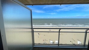 A view from a balcony overlooking a beach with a clear sky and ocean. - Apartment by the Sea with Stunning Views (MIDDELKERKE)
