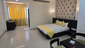 A modern hotel room with a bed, a desk, and a seating area. - HOTEL WESTERN INN (Vasai)