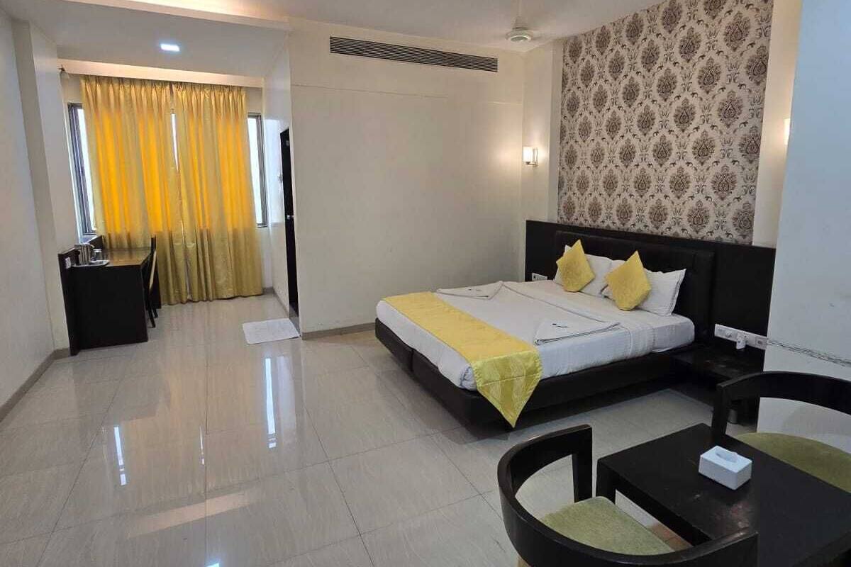 A modern hotel room with a bed, a desk, and a seating area.