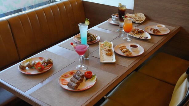 A dining table set with various dishes, drinks, and a view of the outdoors. - HOTEL WESTERN INN (Vasai)