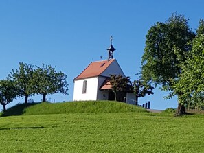 Un piccolo edificio bianco con tetto rosso, una croce sulla sommità e un campanile.