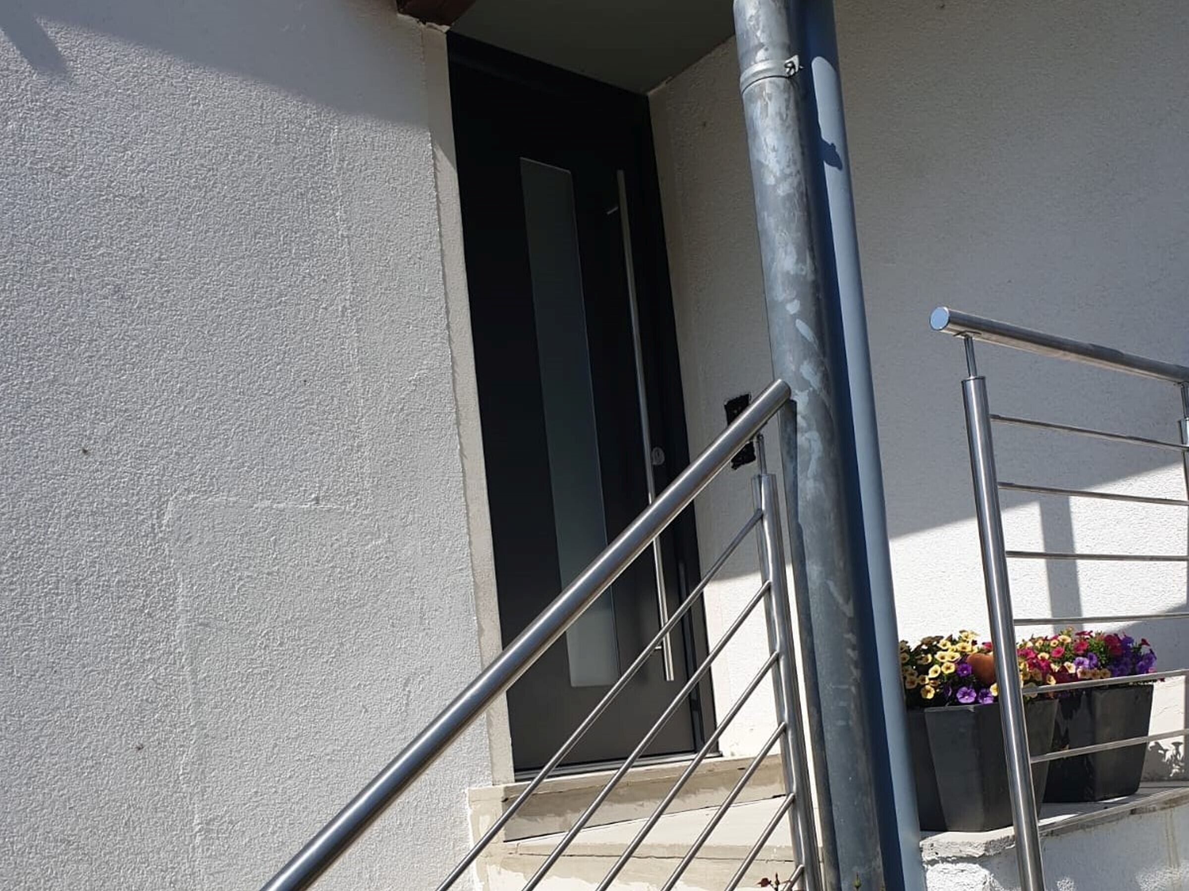 A staircase with metal railings, a door, and potted plants on the landing.