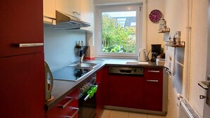 Een kleine keuken met een raam, een klok en een radiator.