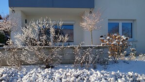 Een modern gebouw met een blauwe gevel, een stenen muur en met sneeuw bedekte beplanting.