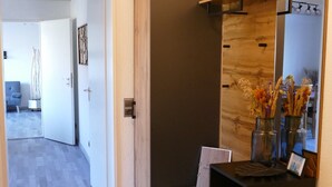 Een gang met een houten kast, een spiegel en een vloerkleed.