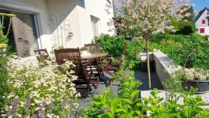 Een gebouw met een balkon, terras en een tuin vol planten.