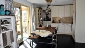 Eine moderne Küche mit einer zentralen Kochinsel, weißen Schränken und Blick durch eine offene Tür auf einen Außenbereich.