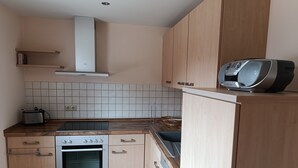 Una cocina con estufa, horno y tostadora, armarios de madera y un microondas en la encimera.