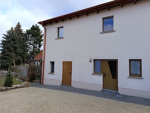 A two-story building with a white exterior, wooden doors, and multiple windows.