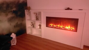 A room with a fireplace, white shelves, and a small white table.