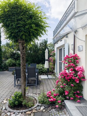 A patio area with outdoor furniture, a tree, and flowering plants. - Holiday Apartment 'Bergblick - Absolute Ruhe' with Mountain View, Private Terrace and Wi-Fi (Scheidegg)