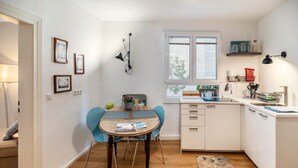 Una cocina compacta con mesa, sillas, una ventana y una pequeña encimera.