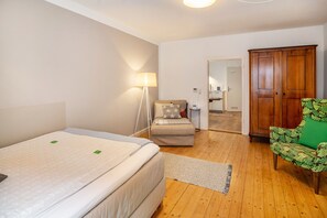 A bedroom with a bed, a chair, a wardrobe, and a lamp.