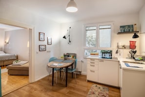 A compact kitchen with a dining area, a small dining table, and a window with blinds.