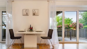 Un coin repas avec une table blanche, deux chaises noires et deux œuvres d’art encadrées accrochées au mur.