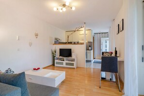 Un salon moderne avec un canapé blanc, une table basse, un téléviseur à écran plat et un coin repas comprenant une table et des chaises.