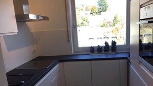 A compact kitchen with a window, a stove, and cabinets. - 'Saschas' Holiday Apartment with Lake View, Balcony, and Wi-Fi (Überlingen)