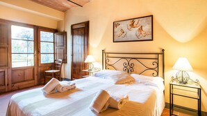 A double bed with white linens, two bedside lamps, and a painting of cherubs on the wall. - Cottage in Tuscany with Pool & BBQ (San Casciano in Val di Pesa)