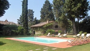 A pool area with a tiled deck, surrounded by grass and trees. - Cottage in Tuscany with Pool & BBQ (San Casciano in Val di Pesa)