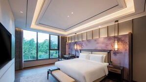 Une chambre d’hôtel moderne avec un grand lit, un banc, un bureau et une télévision.