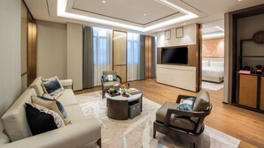 Un salon moderne comprenant un canapé, des fauteuils, une table basse et un téléviseur.
