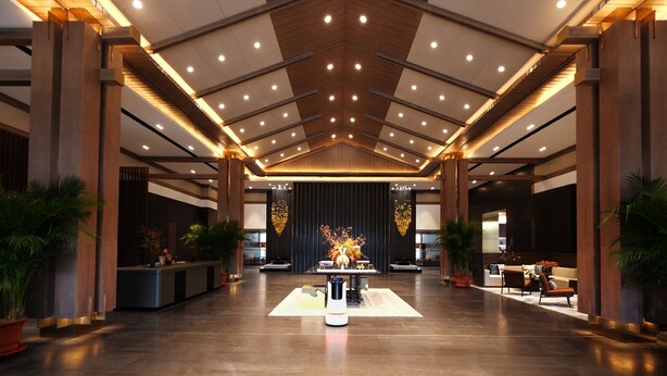Un hall d’entrée spacieux avec un plafond haut, un éclairage moderne et un comptoir d’accueil central.