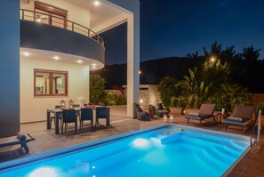 A modern outdoor pool area with a dining setup and lounge chairs.