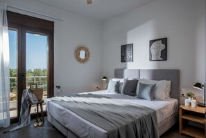 A modern bedroom with a large bed, a view through a sliding door, and two abstract wall art pieces.