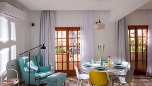 A dining area with a table set for four, a teal armchair, a yellow chair, and a white chair.