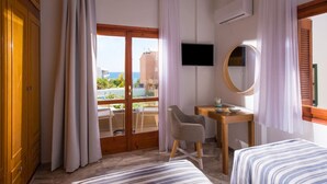 A hotel room with a balcony, a desk with a chair, a bed, a TV, and a mirror.