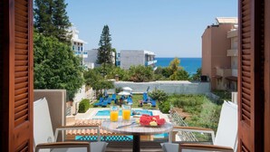 A pool area with lounge chairs, a table with drinks, and a view of the sea.