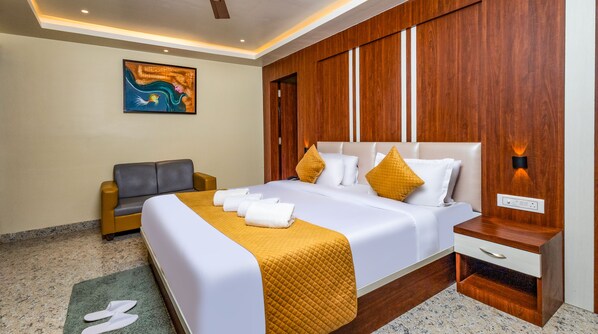 A hotel room with a bed, a sofa, a painting on the wall, and a nightstand with a lamp. - Yashshree Bangla Queen (Kanthi)