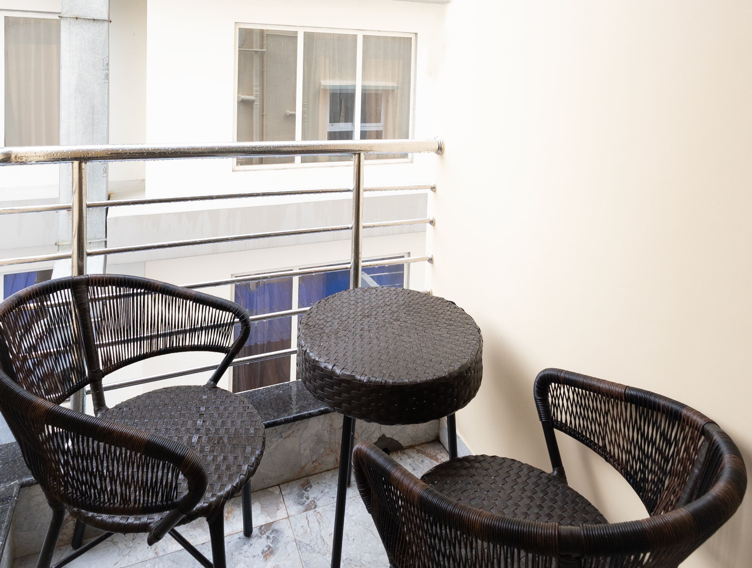 A balcony with two wicker chairs and a small round table.