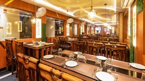 A restaurant with wooden tables and chairs, ceiling fans, and pendant lights. - Yashshree Bangla Queen (Kanthi)