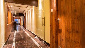A hotel corridor with a wooden door labeled "101", a glass door, and a marble floor with a geometric pattern. - Yashshree Bangla Queen (Kanthi)