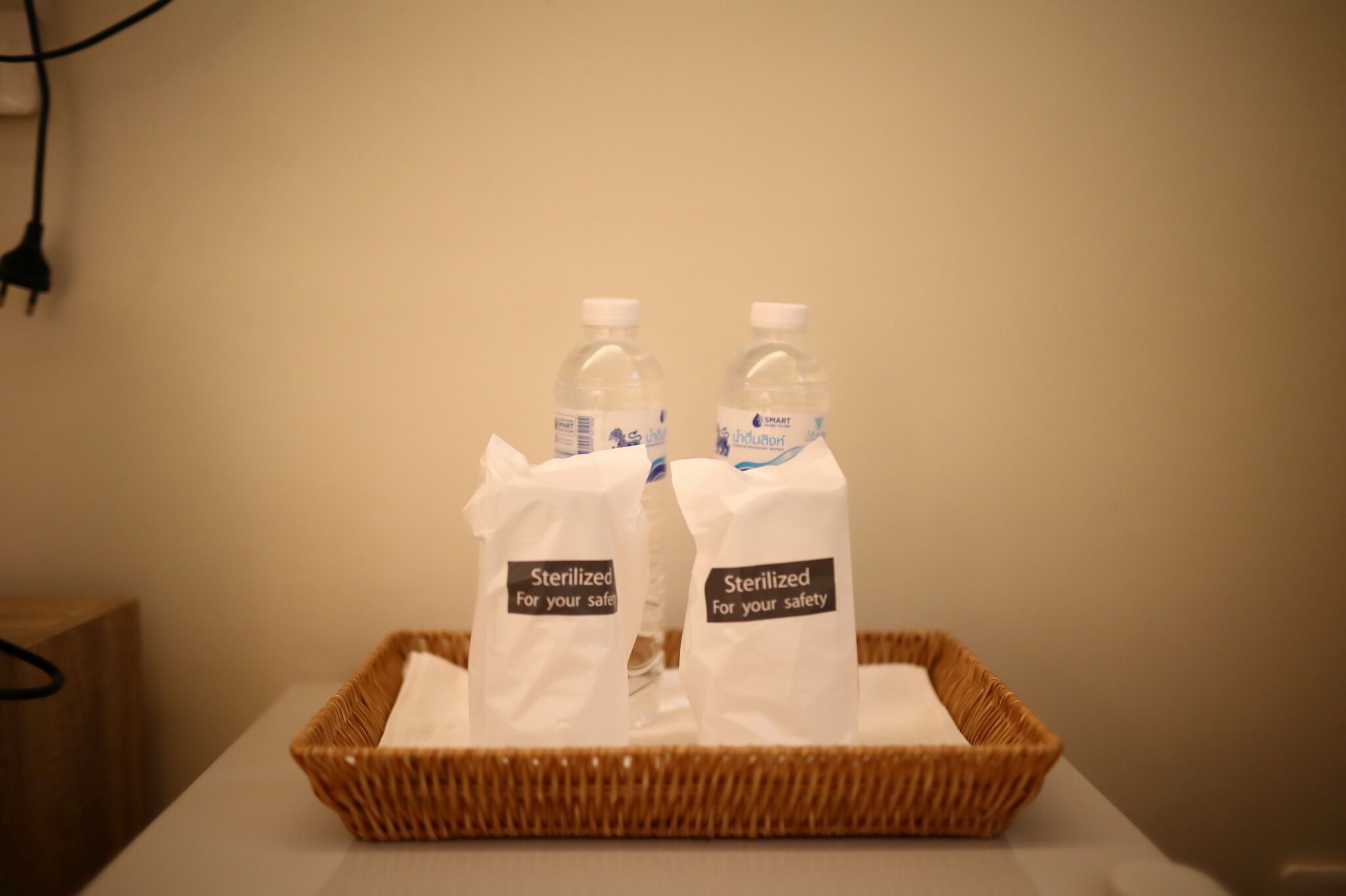 A wicker basket containing two water bottles labeled "Sterilized for your safety" on a table.