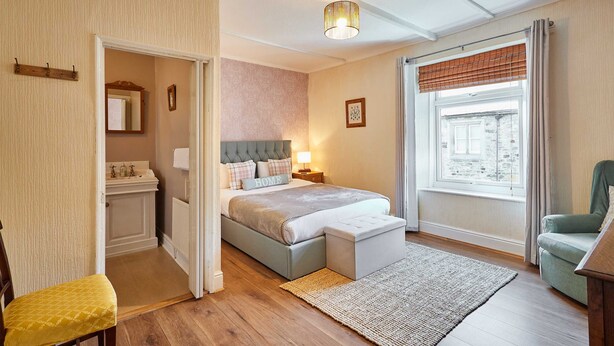 A bedroom with a bed, bedside table, lamp, window with curtains, and a chair. - Host Stay Baliol Street (Barnard Castle)