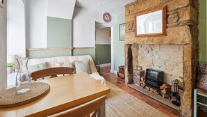 A cozy living room with a stone fireplace, a wooden table, and a comfortable seating area. - Host Stay Baliol Street (Barnard Castle)