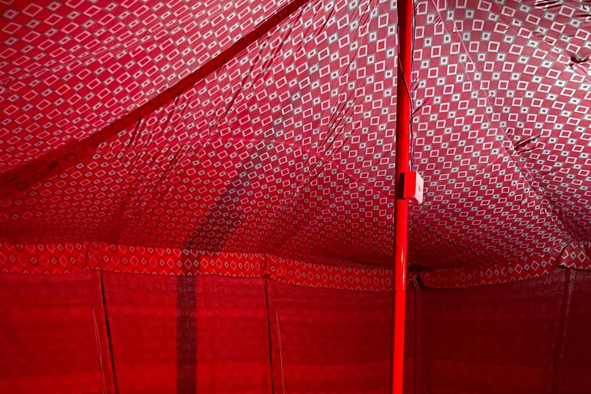 A tent-style room with a bed, pillows, and a red canopy.