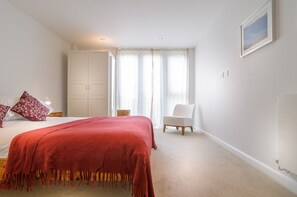 Une chambre à coucher avec un lit, une chaise, une armoire et une fenêtre avec des rideaux.