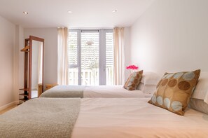 Une chambre avec deux lits, un miroir et une fenêtre avec des stores.