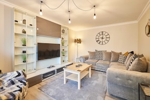 A modern living room with a sofa, a coffee table, a TV, and a bookshelf. - Host Stay Eskdale Escape (Whitby)