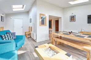 A modern living room with a teal sofa, a wooden dining table, and a skylight. - Host Stay Eskdale Escape (Whitby)