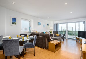 En moderne stue med spiseplads, store vinduer og en balkon.