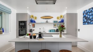 A modern kitchen with a central island, built-in appliances, and a decorative backsplash.